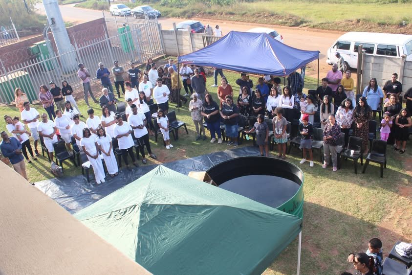 Families and friends watching a baptism service outdoors